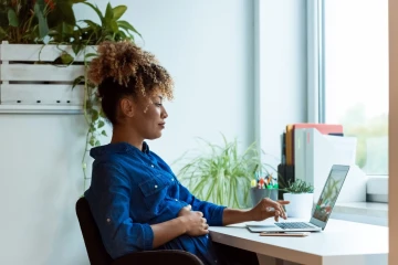 Op de afbeelding is een jonge vrouw te zien die aan een laptop zit te werken.